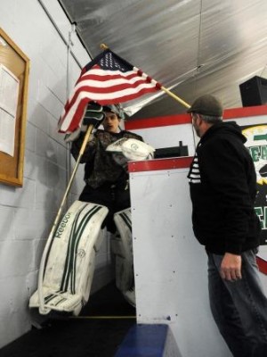 Mike Morse takes the ice as Bob Morse holds Old Glory above him.   (Photo Courtesy Marc Vasconcellos/The Enterprise)