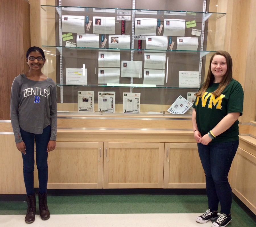 Nivetha Aravindan and Allison Dennehy in front of the Green Wave Gazette display 