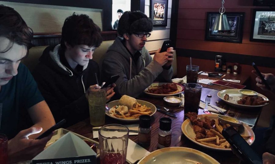 Abington students gather together while on their phones at a local restaurant after school on the half day Friday, Jan. 25. Left to right are Sean Moran 20, Griffin Winters 21, and Connor Lee 21.