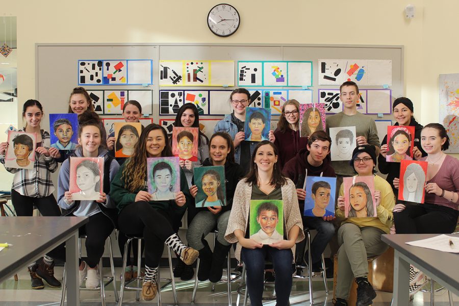 Ms.+Michelle+Poirier+and+her+students+display+portraits+of+the+Filipino+child+whom+they+painted+for+The+Memory+Project.+Seated+left+to+right+are+sophomore+Kaitlyn+Scartissi%2C+junior+Jessica+Rix%2C+sophomore+Cecelia+Lindo%2C+Ms.+Poirier%2C+junior+Jonathan+Aiello%2C+senior+Abi+Edwards%2C+and+sophomore+Madelyn+OLeary.+Standing+left+to+right+are+seniors+Nicole+Marella%2C+Katherine+Marando%2C+and+Abbiejayne+Cristoforo%3B+juniors+Mikayla+Kane%2C+Trinity+OConnor%2C+Daisy+Littlefield%2C+and+Roman+DeBono%3B+and+senior+Laila+Aboudrar.