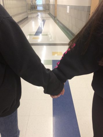 Two students at Abington High School hold hands in the hallway on Friday, December 6, 2019.