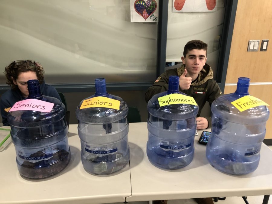 Abington High School freshman Amaya Turner and junior Jack Clifford, members of the Green Wave Gazette, sit with the Penny War containers in the cafeteria on Tuesday, February 11, 2020. They are two of about a dozen students who helped in the fundraiser.