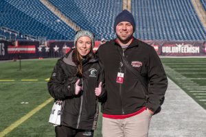 Abington High School athletic trainer Ms. Alicia Reid stands with Bridgewater State Universitys student trainer Dave at Gillette Stadium for the Abington football game on December 7, 2019.
