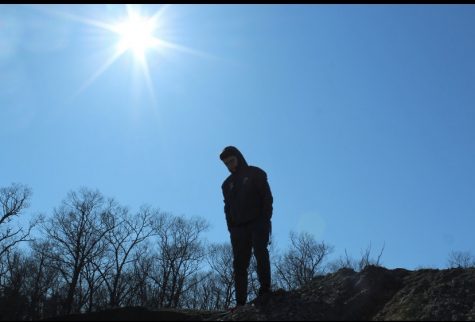 Abington High School senior Jack Clifford (21) stands on top of a dirt mound with sun beaming down on him behind Cherry Berry Shakes and Teas Cafe on Apirl 8, 2020