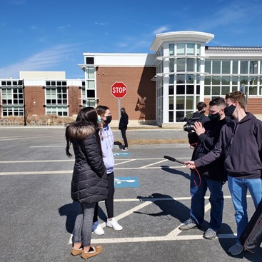 Abington High Schools seniors Aaron Johnson (right front) and Matt Lyons (right rear) of the student newspaper The Green Wave Gazette interview fellow seniors Erin Doherty (front left) and Lily Bonner on March 16, 2021 in front of Abington High School after a fire alarm sounded and the school was evacuated.
