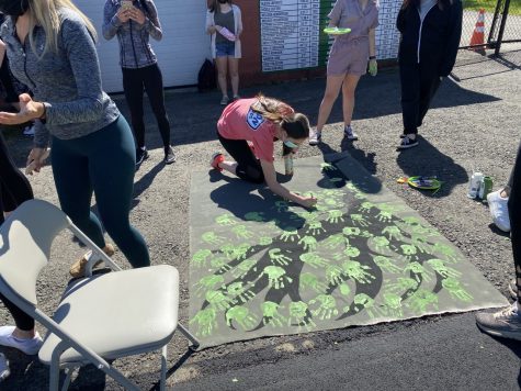 Senior class secretary Carly Mentis holds a hand painting station during the senior event held on Friday, May 14, 2021 at Reilly Field.